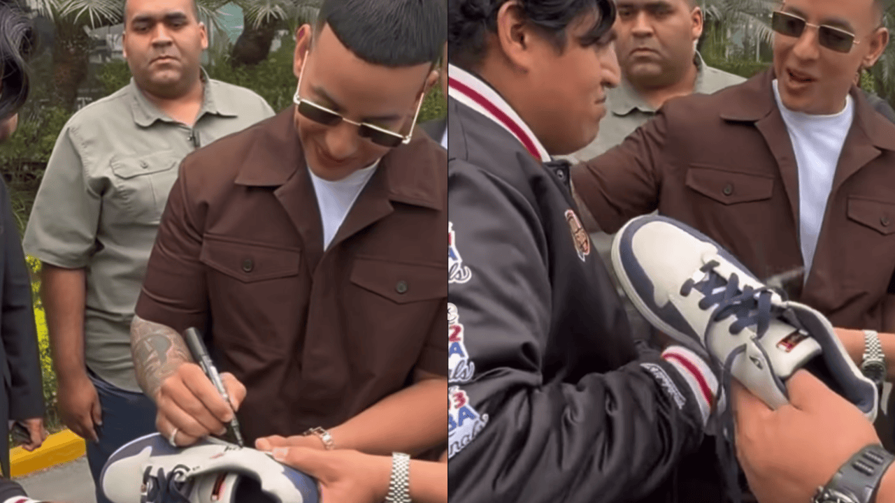 Daddy Yankee firma memorabilia a fan que se le acerca.